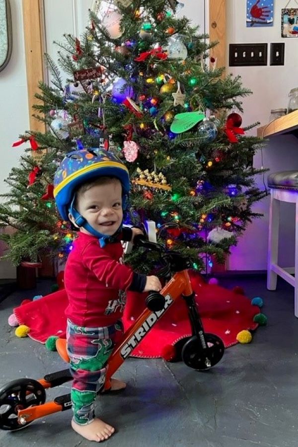 Lincoln Drake smiles as he sits on his adaptive 12" Strider Sport for the first time