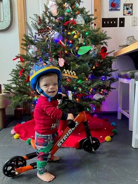 Lincoln Drake smiles as he sits on his adaptive 12" Strider Sport for the first time